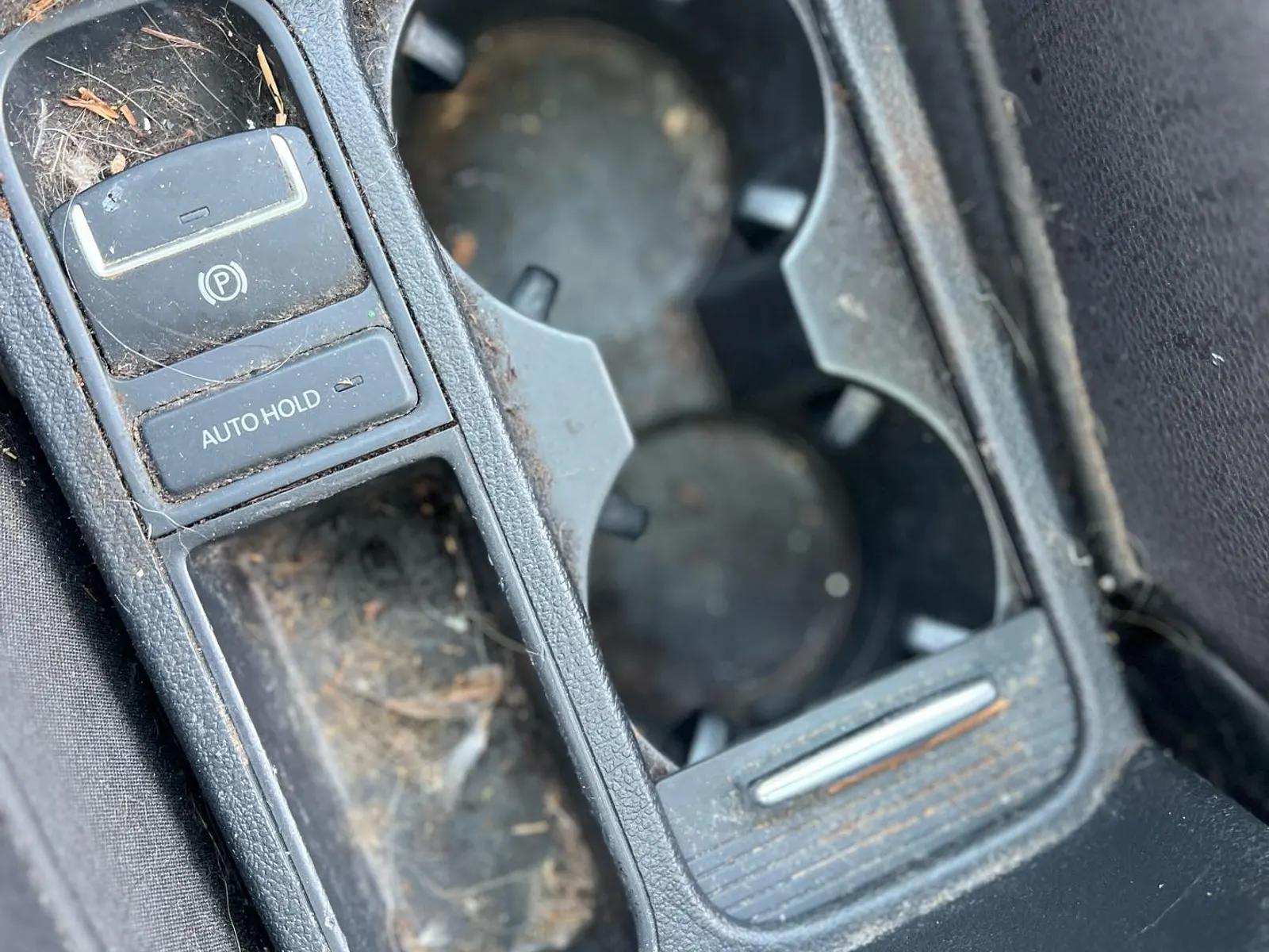 Before — a VW Tiguan center console and cupholders caked with dirt, crumbs, and debris