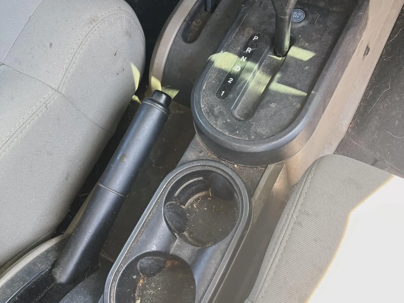 Before — a Jeep Wrangler shifter console and cupholders dirty with grime and debris